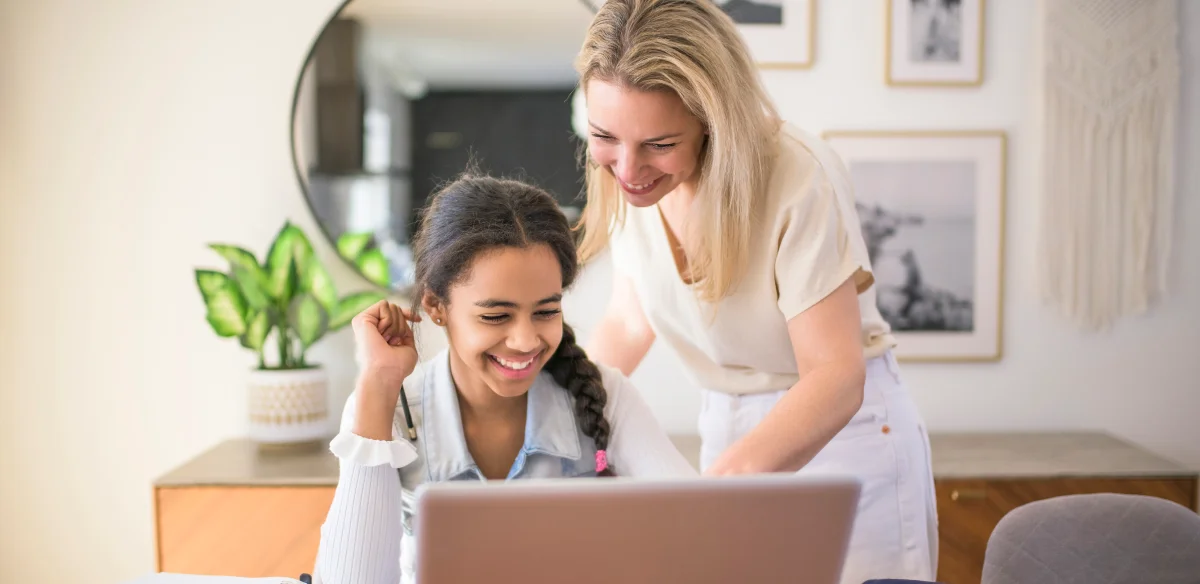 Mother and daughter doing homework together at home with their laptop